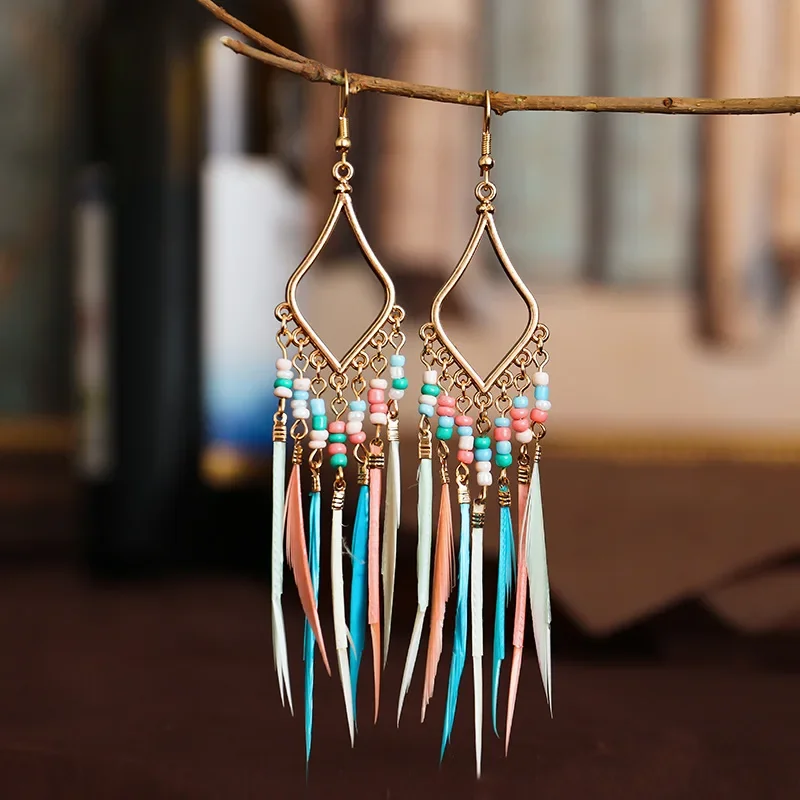 A pair of gold-toned diamond-shaped earrings with colorful beads and hanging plumes.
