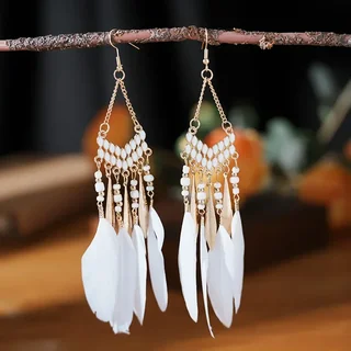 A pair of gold-toned chandelier earrings featuring white beads, metallic teardrops, and white plumes hanging from a branch.