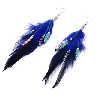 Two long, vibrant blue feather drop earrings with hanging bead strands laid out on a white surface.