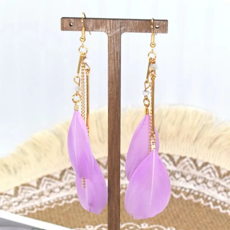 Breeze Feather Drops displayed on a jewelry stand, showing thin metal bars and soft purple feathers.
