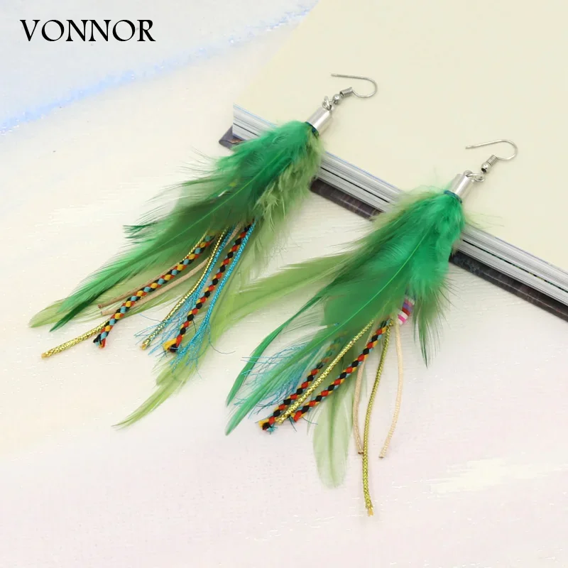A pair of green feather drop earrings with braided, multi-colored cord accents on a white background.