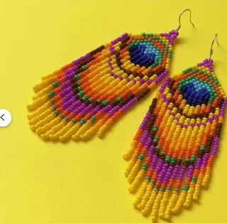 A pair of long, drop earrings made from colorful beads forming a peacock eye pattern with a long fringe bottom.