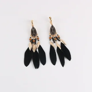 A pair of clip-on earrings featuring a teardrop metal component with geometric patterns, beads, and black feathers.
