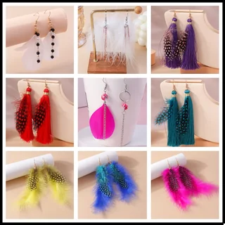 A pair of drop earrings featuring long, wispy plumes and spotted patterns hanging from a gold-toned hook.