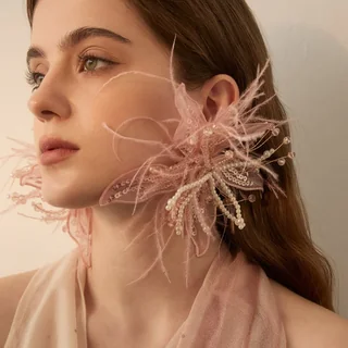 A model wearing a blush-toned feather fan ear accessory with fine strands and bead-like decorative accents.