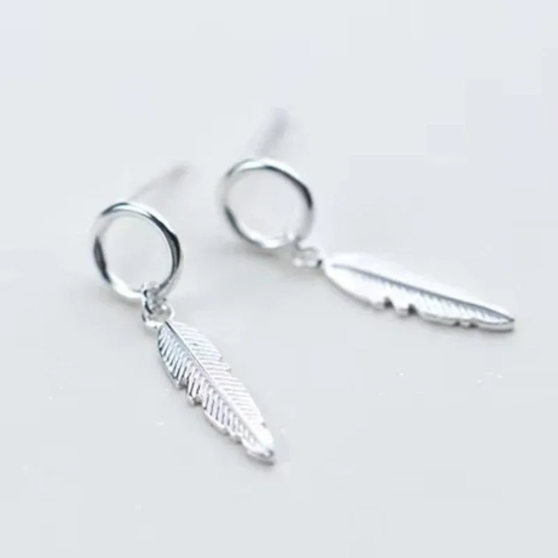 A pair of silver-toned drop earrings featuring a small circular hoop attached to a textured, elongated feather-shaped metal charm.