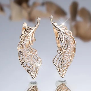 A pair of gold-toned wing-shaped earrings with intricate filigree and small sparkling accents.