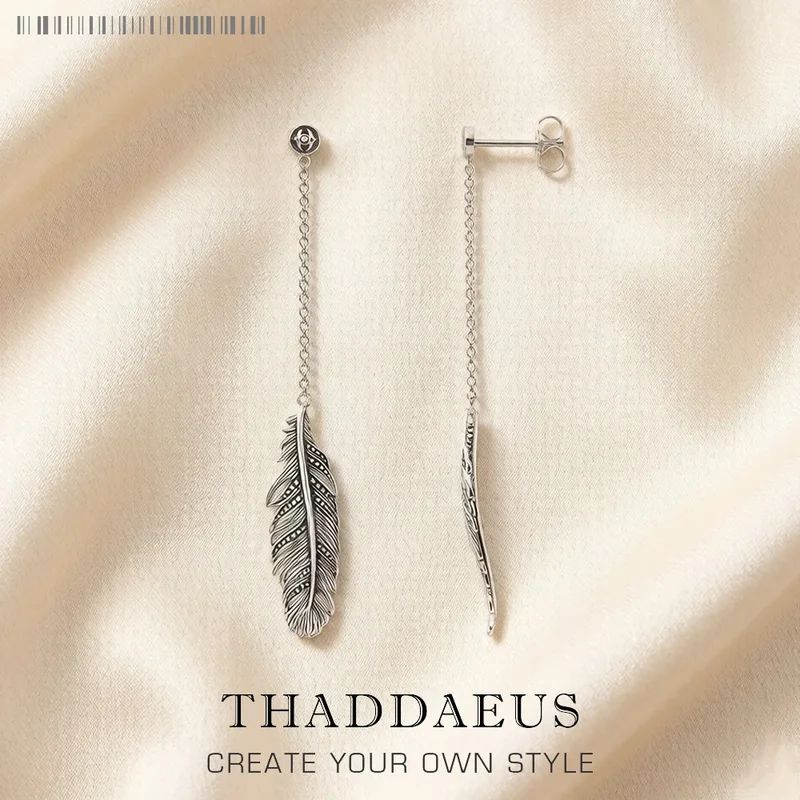 A pair of silver-toned chain threader earrings with a small metal feather charm at the end.