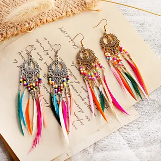 Assorted feather drop earrings with round patterned ornaments, colorful bead accents, and long narrow feather fringe.