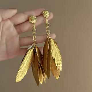 Gold-toned drop earrings with textured round tops, open chain links, and a cluster of overlapping leaf-like feather motifs.