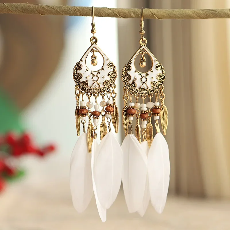 Close-up of Luna Feather Drops showing teardrop frames, beads, metal leaves, and white plumes hanging from gold-toned hooks.