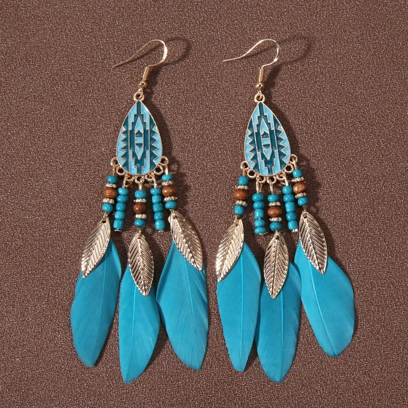 A pair of blue feather drop earrings with oval feather-patterned ornaments, bead strands, and small hanging charms.