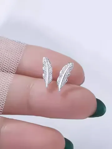 Small stud earrings shaped like a single, etched metallic feather.