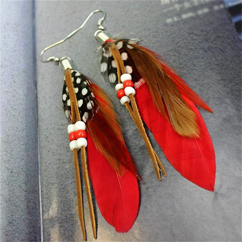 Drop earrings featuring spotted plumes, red plumes, white and red beads, and thin brown suede-like ties.