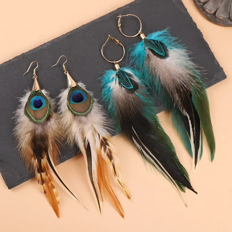 Two pairs of colorful plume feather earrings hanging from gold-tone circular hoops.