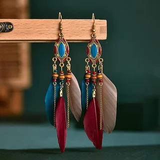 A pair of drop earrings featuring geometric metal frames with blue accents, hanging chains, and layered plumes.