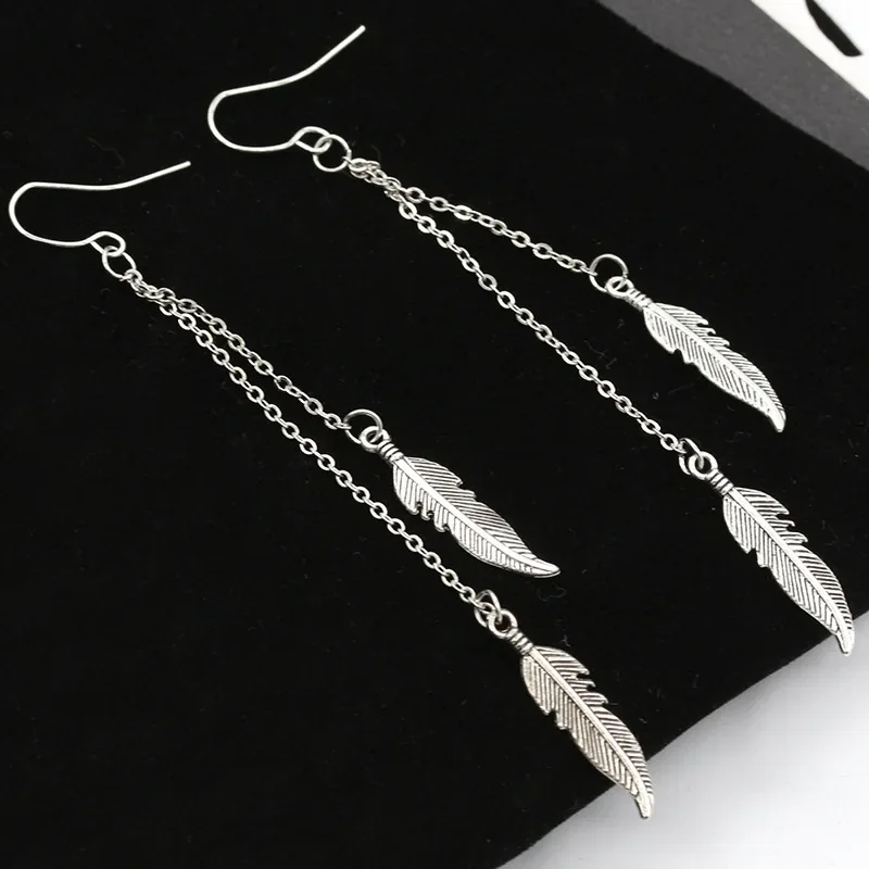 A pair of drop earrings with three thin chains of varying lengths, each ending in a small, engraved metal feather.