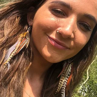 Close-up of a woman wearing Trail Feather Drops with patterned brown and white feathers.