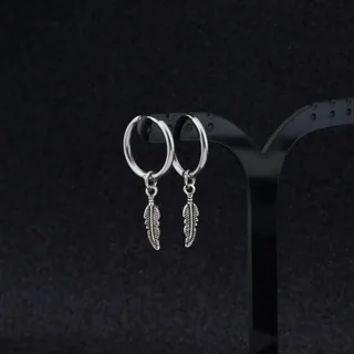 A pair of small, silver-toned hoops with a dangling, etched feather-shaped charm suspended from each.