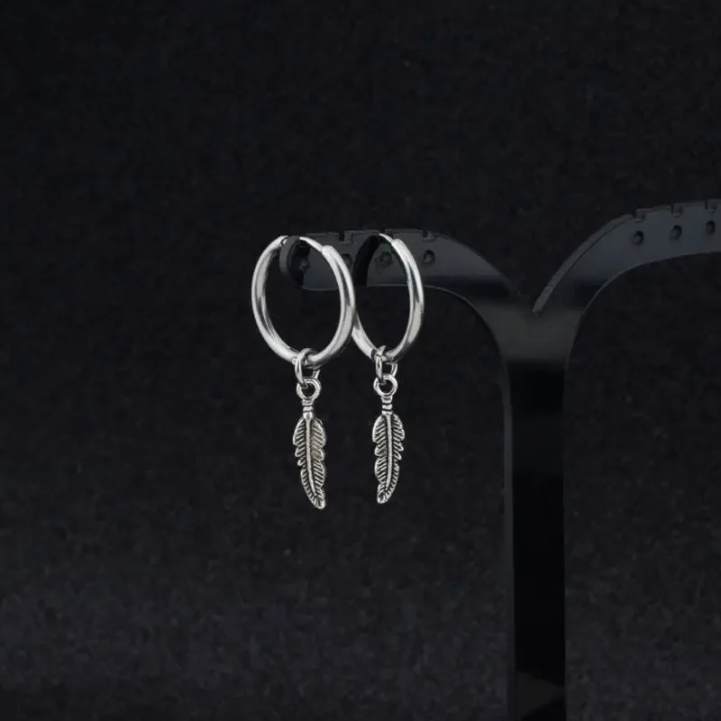 A pair of small, silver-toned hoops with a dangling, etched feather-shaped charm suspended from each.